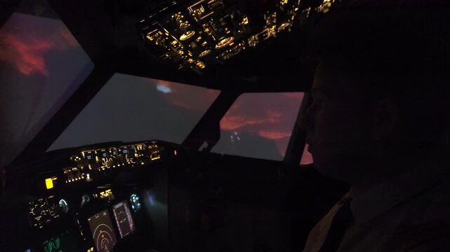 Focused captain navigates aircraft at night. Pilot turns on panel light in cockpit guiding airplane in bad weather conditions