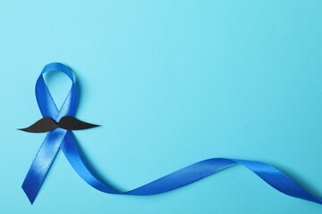 Blue ribbon and fake mustache on color background, top view with space for text. Prostate cancer...