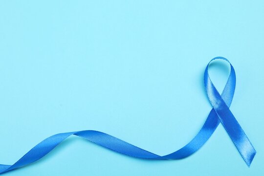 Blue ribbon on color background, top view with space for text. Prostate cancer awareness