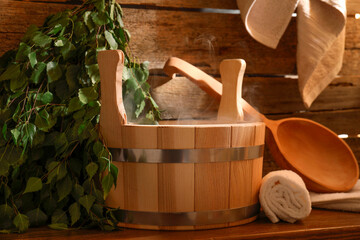 Sauna equipment. Bucket, ladle, birch whisk and towels on wooden table indoors