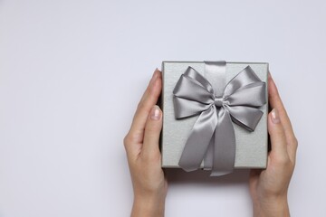 Woman holding gift box with bow on white background, top view. Space for text