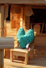 miniature porch scene has a rustic charm. It features a dollhouse setting, light-colored wood, a thatched roof, cozy lounge chairs with turquoise cushions and a small table, place for happy couple