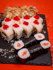 delicious set of rolls featuring fresh maki with salmon, an appetizing roll with red caviar and Philadelphia cheese, and a delightful baked roll on a beautiful red background
