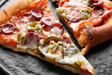 Pieces of delicious pizza Diablo on textured board, closeup