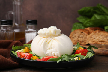 Delicious burrata salad on wooden table, closeup