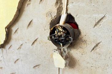 Electrical socket hanging on wall. Old Plug socket hanging off wall in room. Electrical plug. Socket fell out of wall, hangs on wires. Repair old sockets. Construction work to renovation in flat.