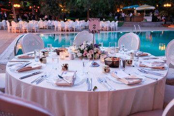 Romantic outdoor wedding reception with round tables, white linens, and floral centerpieces,...