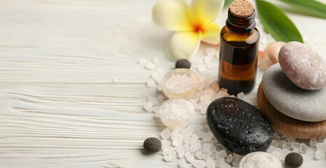 Spa treatment with essential oil, stones, and flower on a white wooden background.