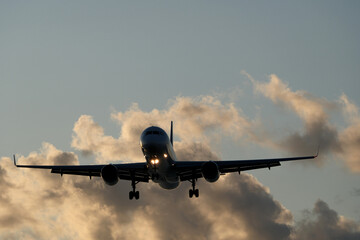 Airplane in the sky with clouds in the evening at the airport