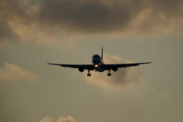 Airplane in the sky with clouds in the evening at the airport