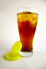 Iced tea with lemon and ice in a tall glass on a white background. The concept of a refreshing drink or lemonade on a hot summer day. Front view and copy space.