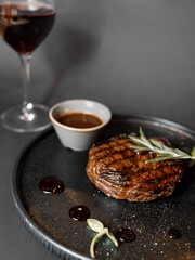 delicious steak with tomato cream sauce, fresh herbs, and a beautiful glass of red wine in a nice restaurant