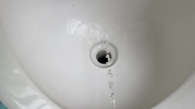 Stream of urine flowing into a white ceramic toilet bowl hole close up shot. Men's restroom.