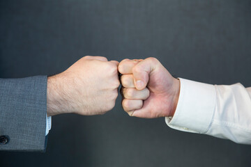 Close up of two unrecognizable businessmen greeting each other with fist bump.