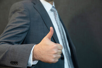 A handsome young businessman is smiling and giving the thumbs up sign.