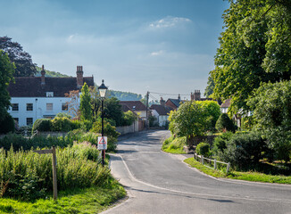 A peaceful village street in Buriton, Hampshire with a maximum 20mph speed limit sign in the foreground.