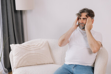 Home, senior man and headache on sofa for stress, emotional conflict and temporal vertigo. Living...