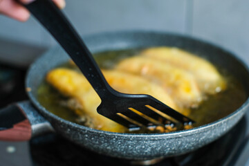 Fried banana in a pan with hot oil and spatula. Banana deep fried is a popular street food in Indonesia