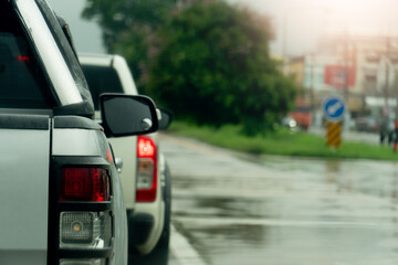 Rear side view of pickup car white color stop on the wet asphalt road. In front is a road island with lush green grass and trees. in Thailand. © thongchainak
