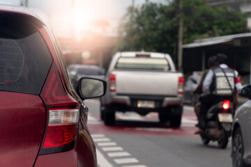 Rear side of red car on the asphalt road. Many cars driving on the road with pickup car and motorcycle. Small community environment in Thailand. © thongchainak