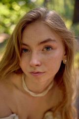 Naklejka premium beautiful teenage girl in a silk skirt and a corset in the old money style walks in the park and along the river bank