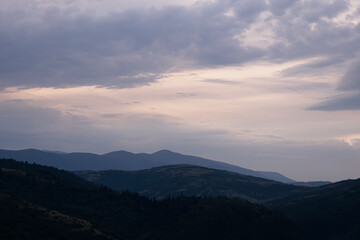 Gently pink sunset with the setting sun behind the mountains.