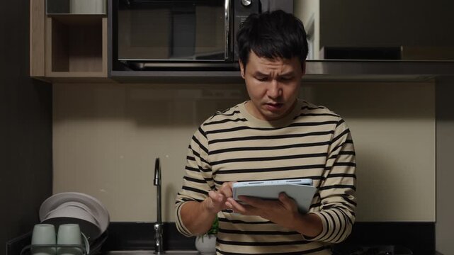 stress man using tablet computer in the kitchen