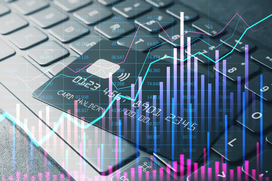 Credit card on laptop keyboard with financial graphs overlay. - Powered by Adobe