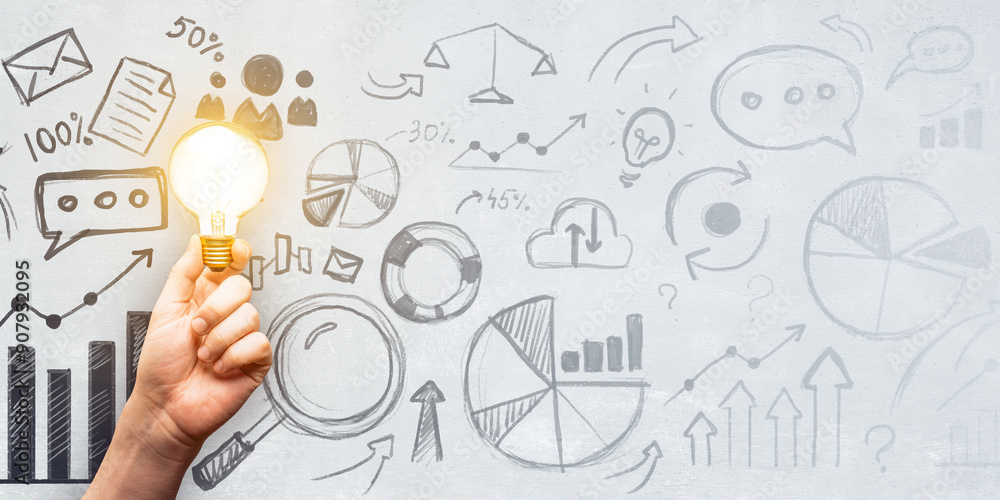 Poster hand holding bright lightbulb against a background of business sketches and charts.