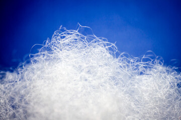 Extreme macro of polyester stable fiber on blue background. Selective focus, shallow depth of field. Abstract dreamy background