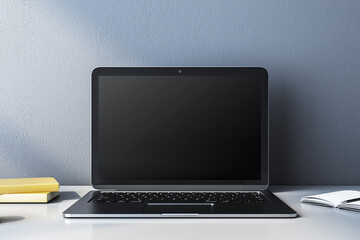 Modern laptop with blank screen on a desk, books and notebook beside it. 3D Rendering