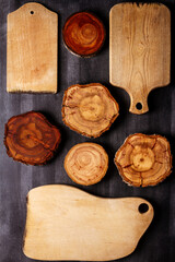 Old wooden cutting boards and tree trunk slices on black chalkboard background. Flat lay. Top view. Food concept.