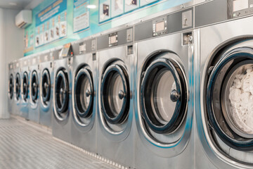 Row of washing machines in public laundry. Commercial cleaning services or utility management in communal spaces. Laundromat. Shared amenities. Self-service, coin laundry, or coin wash.