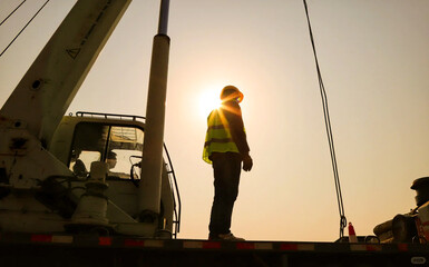 Man wearing safety gloves stands at the controls of a truck, communicating directly with the truck...