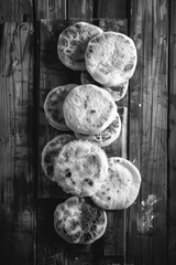 A stack of round pastries on a wooden table. The pastries are all different sizes and are arranged in a neat stack. The image has a simple and elegant feel to it