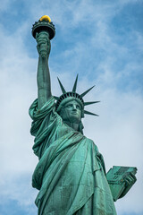 Fototapeta premium New York, NY, USA - August 4, 2023: Miss Liberty statue torso closeup, against blue cloudscape