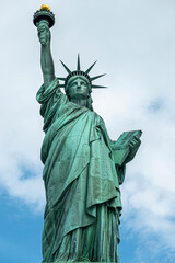 Fototapeta premium New York, NY, USA - August 4, 2023: Miss Liberty statue full body closeupl, against white cloud