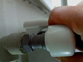 Turning the tap on the heating radiators. The topic of saving heat. A man turns off the heating in the house with his hand.