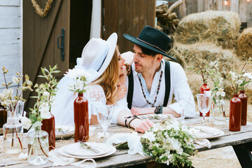 wedding boho style ceremony young couple newlyweds bride in white dress with veil and groom in hat and jeans with suspenders hugging and having fun at barn of country house, shot in motion