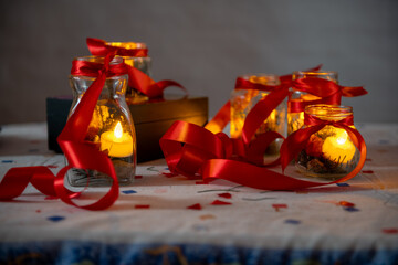 Candlelight in glass jars with red ribbons, creating a cozy festive atmosphere