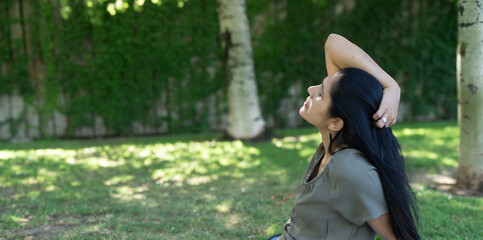 Naklejka premium A woman is sitting in the grass and looking up at the sky