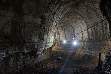 Illuminated interior of a dark tunnel with rugged walls and rock formations