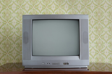 Old TV on the nightstand against the background of wallpaper.