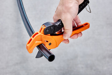 Ratcheting plastic pipe and tube cutter for one hand operation.
