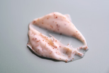 A smear of cream scrub on a green background. Texture of a cosmetic product.