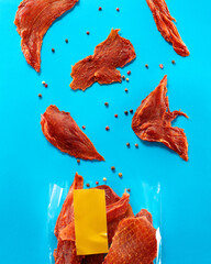 Open package of meat jerky on bright blue background