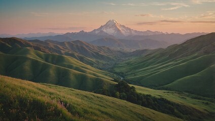 Beautiful mountain scenery at sunset, with towering mountains and a foreground of soft, green grass