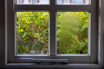 Wooden frame double glazed window showing condensation droplets between two panes of glass separated by a layer of insulating gas