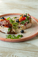 plate with bruschetta with cream cheese, tomatoes and bresaola on a light table, top view