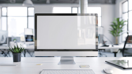 Fototapeta premium Modern office desk setup with a blank computer screen, potted plant, and sleek accessories in a bright workspace.
